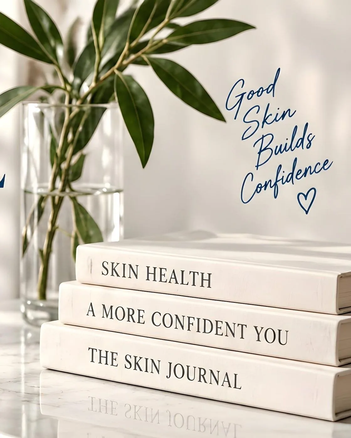 A glass vase of green leaves beside a stack of books titled Skin Health, A More Confident You and The Skin Journal. Lettered on the wall: Good skin builds confidence.